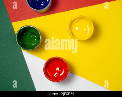 Gläser mit gelber, grüner und roter Farbe auf farbigem Hintergrund. Ufer der Gouache. Heller Hintergrund. Kreativ . Künstlerwerkstatt. Stockfoto