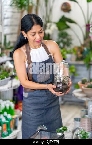 Frau in ihrem Blumengeschäft, die sich um ihre kostbaren Blumen kümmert Stockfoto