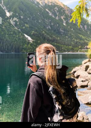 Junge Frau fotografiert den Bergsee Morskie oko in der Tatra Stockfoto