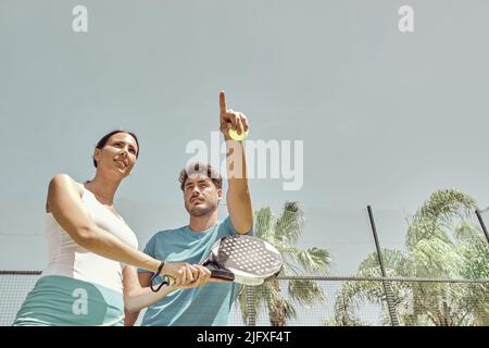 Monitor, der einer Frau, seiner Schülerin, Paddeltenniskurse gibt Stockfoto