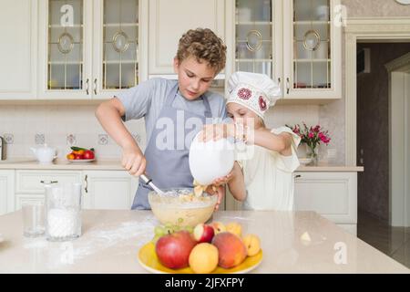 Kinder bereiten Apfelkuchen in der Küche zu. Stockfoto
