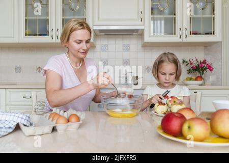 Mama und Tochter kochen gemeinsam in der Küche Apfelkuchen. Stockfoto