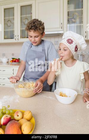 Kinder haben Spaß beim Kochen von Apfelkuchen in der Küche. Stockfoto