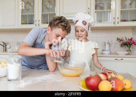 Bruder und Schwester kochen gemeinsam in der Küche Apfelkuchen. Stockfoto