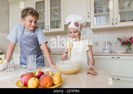 Kinder in der Küche bereiten Teig für Apfelkuchen zu. Stockfoto