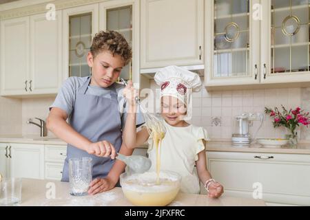 Kinder bereiten in der Küche Teig für Apfelkuchen zu. Stockfoto