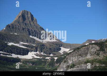 Glacier National Park Montana USA - Logan Pass, Road to the Sun, strahlend blauer Himmel über dem majestätischen Reynolds Mountain Peak mit schmelzenden Schneefällen Stockfoto