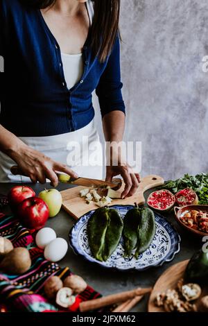 mexikanische Frau Kochen Chiles en nogada Rezept mit Poblano Chili und Zutaten, traditionelles Gericht in Puebla Mexiko Stockfoto