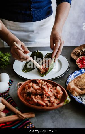 mexikanische Frau Kochen Chiles en nogada Rezept mit Poblano Chili und Zutaten, traditionelles Gericht in Puebla Mexiko Stockfoto