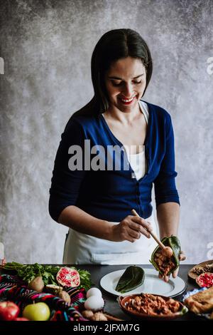 mexikanische Frau Kochen Chiles en nogada Rezept mit Poblano Chili und Zutaten, traditionelles Gericht in Puebla Mexiko Stockfoto