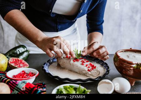 mexikanische Frau Kochen Chiles en nogada Rezept mit Poblano Chili und Zutaten, traditionelles Gericht in Puebla Mexiko Stockfoto