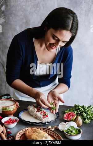 mexikanische Frau Kochen Chiles en nogada Rezept mit Poblano Chili und Zutaten, traditionelles Gericht in Puebla Mexiko Stockfoto