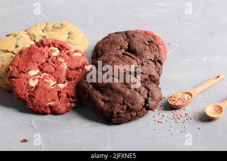 Verschiedene weiche amerikanische Plätzchen, Vanille, roter Samt und dunkle Schokoladenchips auf rustikalem Tisch. Platz für Text oder Rezept kopieren Stockfoto