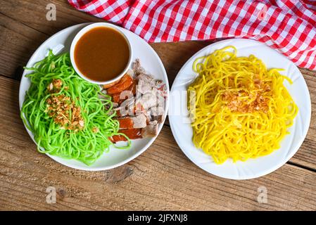 Jade Nudel und gelbe Nudeln Asiatische Thailand Essen, geröstete Ente mit Jade Nudel auf weißem Teller und Entensoße Holzhintergrund, grüne Nudeln Chi Stockfoto