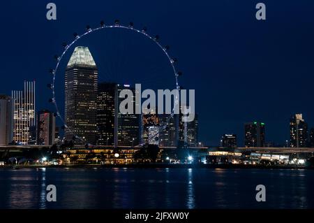 Downtown Singapore bei Nacht, mit dem Singapore Flyer Beobachtungsrad im Vordergrund Stockfoto