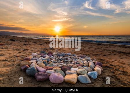 Während des Sonnenuntergangs am Strand werden rituelle Steine für spirituelle Zeremonien in Einem Kreis angeordnet Stockfoto