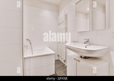 Waschbecken mit Spiegeln und sauberer Badewanne im modernen Badezimmer mit weiß gefliesten Wänden Stockfoto