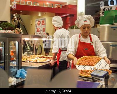 Uniformierte Mitarbeiter bereiten Pizza bei Sbarro Pizza im Jervis Shopping Centre in Dublin, Irland, zu. Stockfoto