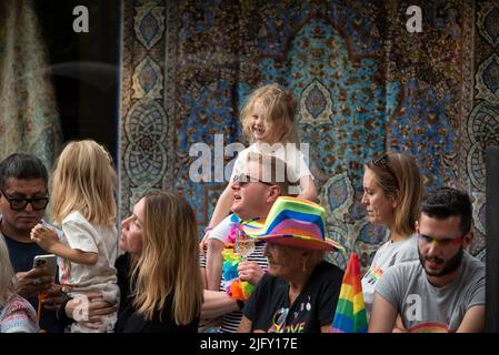 Piccadilly, London, Großbritannien. 2.. Juli 2022. London Pride März 2022. Wir feiern 50 Jahre Pride in Großbritannien und folgen der gleichen Strecke im Zentrum Londons, die 1972 genommen wurde. Menschen am Straßenrand beobachten den London Pride-marsch mit Kind auf den schultern von menschen. Kredit: Stephen Bell/Alamy Stockfoto