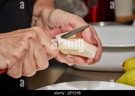 Der Koch schneidet die Birnen in Scheiben für den Schokoladenkuchen mit Birne und Nüssen. Schritt für Schritt Rezept Stockfoto