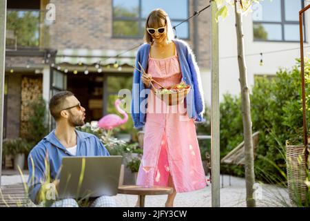 Glückliche junge Familie mit Laptop und einem gesunden Mittagessen im Hinterhof Stockfoto