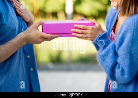 Der Mann schenkt seiner Frau im Freien ein Geschenk in rosa Schachtel Stockfoto