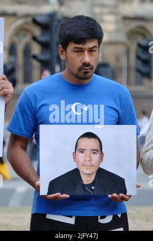 London, Großbritannien, 5.. Juli 2022. Uigurische Aktivisten und andere Unterstützer versammelten sich auf dem Parliament Square und hielten Fotos von vermissten Personen, als sie den 13.. Jahrestag des tödlichen Aufruhrs von Urumqi ankündigten, Die die Räder für die Kommunistische Partei Chinas (KPCh) in Bewegung setzte, um einen Überwachungsstaat in der Region Xinjiang einzuführen, zusätzlich zu Internierungslagern, Zwangsarbeit, Sterilisation und anderen Menschenrechtsverletzungen. Kredit: Elfte Stunde Fotografie/Alamy Live Nachrichten Stockfoto