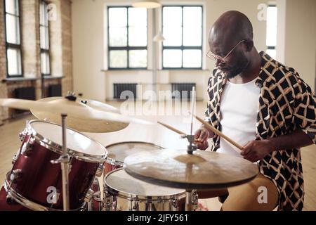 Afrikanischer junger Schlagzeuger hinter dem Schlagzeug, der im Studio Schlagzeug spielt Stockfoto