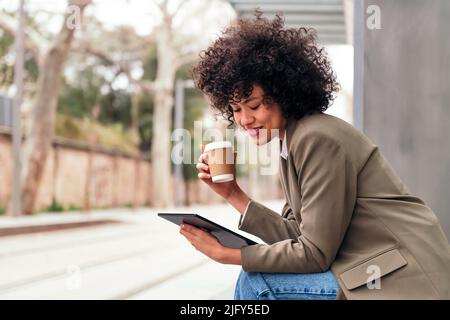 Frau, die ihr Tablet benutzt, während sie auf den Bus wartet Stockfoto