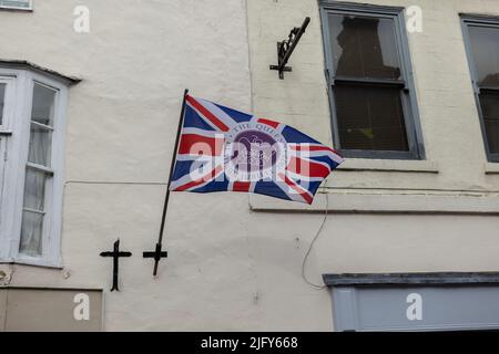 Winkende Union Jack-Flagge auf der Seite des Gebäudes für die Feier des britischen Queens Jubilee 2022 in Knaresborough, Yorkshire Stockfoto