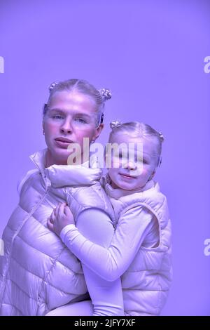 Virtuelle Technologie. Glücklich erfreut nettes Mädchen lächelnd und Blick auf die Kamera, während Mutter in ihren Armen in digitalen virtuellen Brille auf der Bienge hält Stockfoto