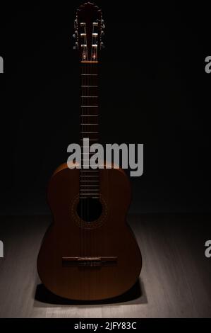 Spanische klassische Gitarre dramatisch beleuchtet von oben auf einem schwarzen Hintergrund. Stockfoto