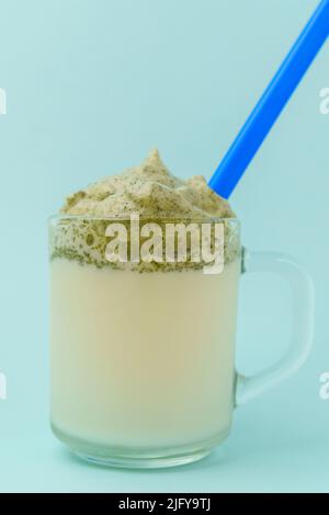 Dalgona Matcha Latte, blauer Hintergrund. Matcha grüner Tee. Trendiges Getränk. Superfoods. Milchgetränk. Koreanischer Drink Stockfoto