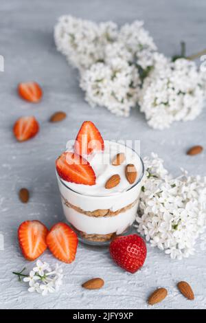 Ricotta-Dessert mit frischen Erdbeeren. Gesundes Frühstück mit Joghurt, Erdbeere und Mandeln Stockfoto