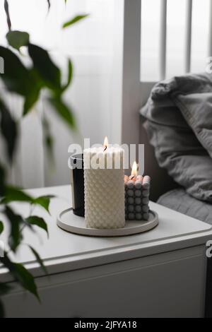 Luxuriöse Duftkerze im Schlafzimmer auf dem Betttisch. Home gemütliche Innenausstattung. Stockfoto