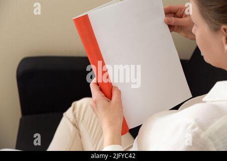 Die Hand hält ein weißes Magazin mit leerem Deckblatt. Hand in Hemd halten klar Magazin Mockup Vorlage. A4 Buch Softcover Oberflächengestaltung. Stockfoto