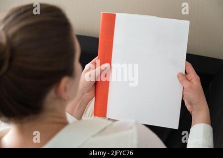 Die Hand hält ein weißes Magazin mit leerem Deckblatt. Hand in Hemd halten klar Magazin Mockup Vorlage. A4 Buch Softcover Oberflächengestaltung. Stockfoto