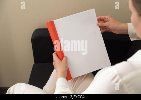 Die Hand hält ein weißes Magazin mit leerem Deckblatt. Hand in Hemd halten klar Magazin Mockup Vorlage. A4 Buch Softcover Oberflächengestaltung. Stockfoto