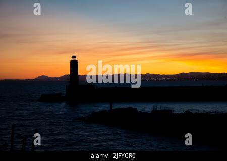 Sonnenuntergangslandschaft, die das Meer, den Leuchtturm und die Berge von Nizza, Frankreich, einfängt. Stockfoto