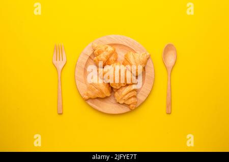 Draufsicht Mini Croissant in Holzschale auf gelbem Hintergrund. Food-Konzept mit Kopierraum Stockfoto