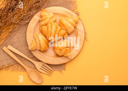 Draufsicht Mini Croissant in Holzschale auf gelbem Hintergrund. Food-Konzept mit Kopierraum Stockfoto