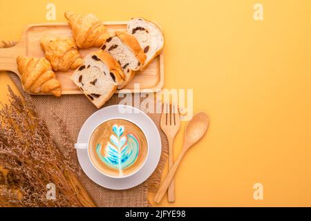 Draufsicht Mini Croissant und Brot in Holzschale und Kaffee auf gelbem Hintergrund. Food-Konzept mit Kopierraum Stockfoto