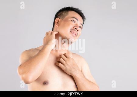 Health Care oder Juckreiz oder Tinea cruris Konzept : Porträt von Menschen mit Händen zu kratzen an seinem Körper. Studio auf grauem Hintergrund aufgenommen Stockfoto