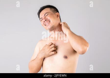 Health Care oder Juckreiz oder Tinea cruris Konzept : Porträt von Menschen mit Händen zu kratzen an seinem Körper. Studio auf grauem Hintergrund aufgenommen Stockfoto