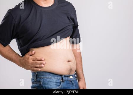 Körperschmerzen, Hüftschmerzen oder Auswirkungen von Leberproblemen : fetter Mann mit der Hand und Druck auf die Hüftposition. Studio auf grauem Hintergrund aufgenommen. Stockfoto