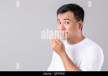 Gesundheitswesen : Mann überprüft seinen Atem mit der Hand. Portrait Asian Mann sind im Studio auf grauem Hintergrund aufgenommen zu ermatten Stockfoto