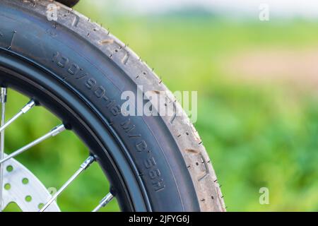 Makronummer-Code am vorderen Motorrad-Gummirad. Außenaufnahmen auf der Straße mit Kopierplatz Stockfoto