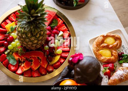 Eine Draufsicht auf Wassermelone, Erdbeeren, Kirschen, Trauben, Himbeeren, Trauben, Ananas und Kiwi, neben anderen Süßigkeiten Stockfoto