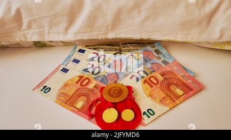 Geld oder Euro, Dollar und Goldmünzen unter dem Kissen oder auf weißem Hintergrund, traditionelle Investition. Stockfoto