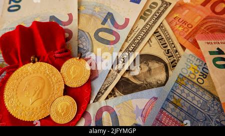 Foto von oben mit Geld-, Euro-, Dollar- und Goldmünzen auf dem roten Hintergrund. Stockfoto